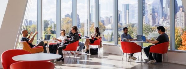 Students sitting at Cornell Tech, NYC skyline in background
