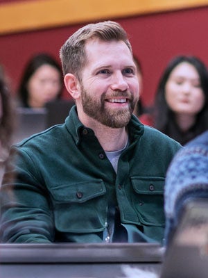 Cornell student smiling and listening during a hospitality management lecture.