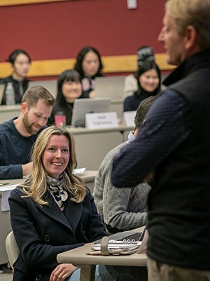 Woman smiling at professor during master of management in hospitality lecture.