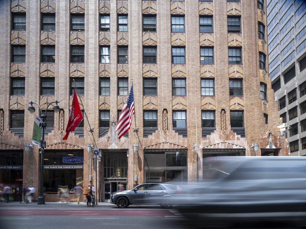 A building in NYC with a car rushing past.