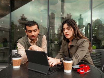 Two business analytics students reviewing data on a laptop