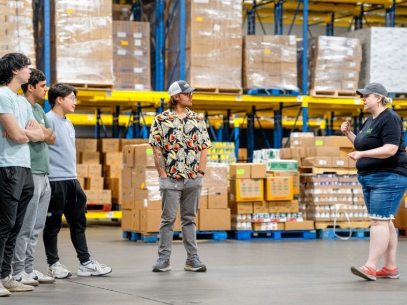 A group of people stand in a warehouse.