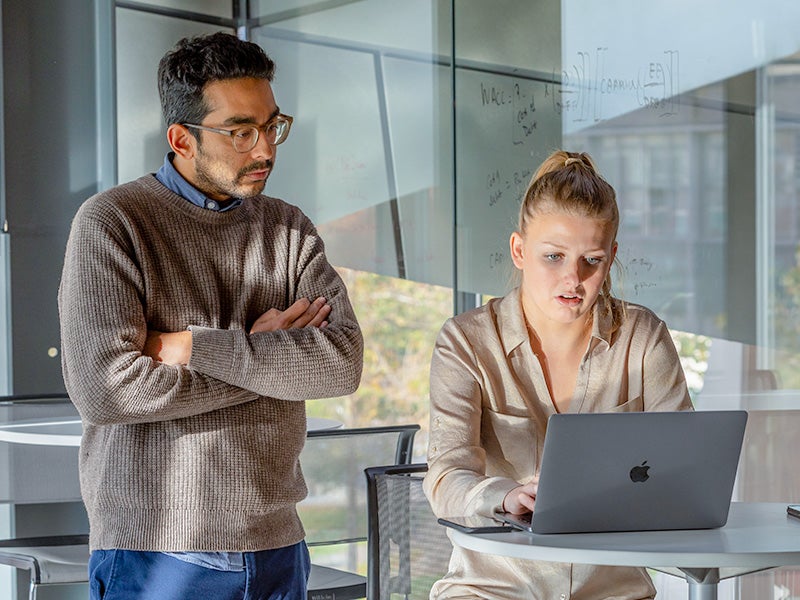 Two Cornell MMH students review a document together on a laptop