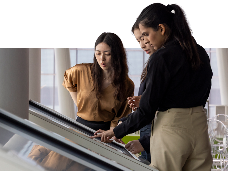 Two female students on a Singapore TREK looking at a board or building layout