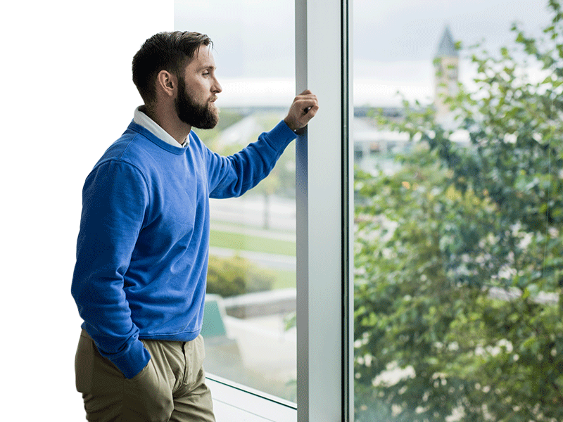 Adult student in business casual overlooking Feeney way in fog tower in background