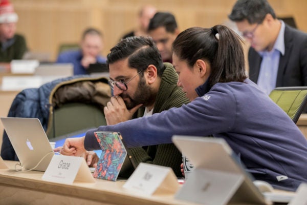 A woman points to a laptop screen while collaborating with a man in the classroom