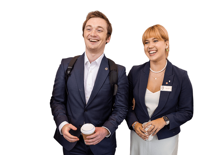 Male and female Nolan undergraduates with coffee smiling at an event in atrium.