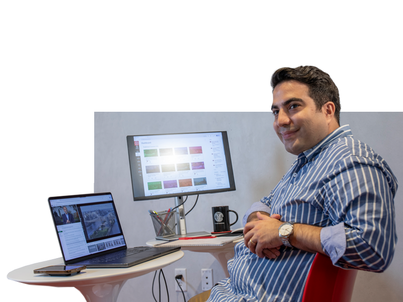 student sitting at desk at home, two monitors
