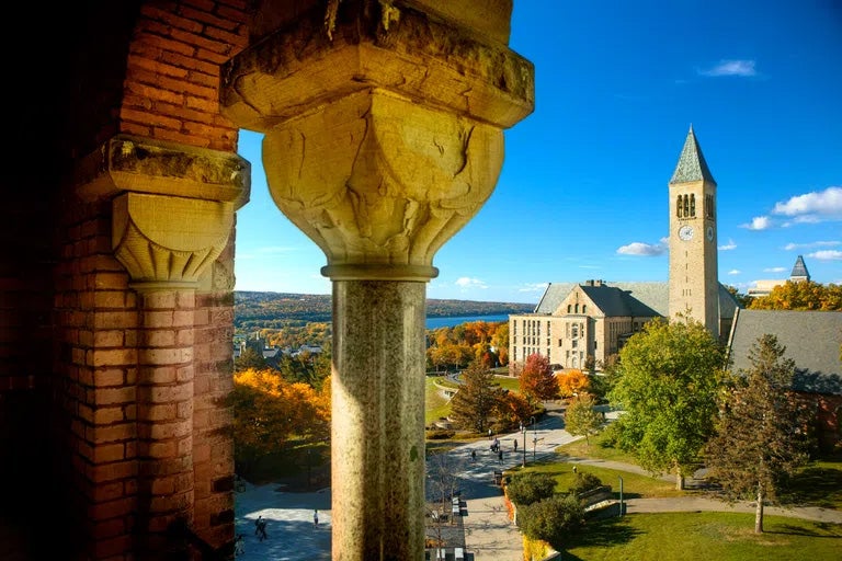 Stone arches on a sunny day with Cornell University's McGraw clock tower and Cayuga Lake in the background