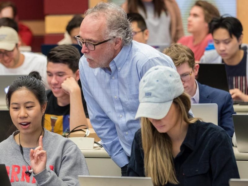 Nolan School faculty assists a young women undergraduate student during a project in a lecture hall as part of the B.S. in Hotel Administration program