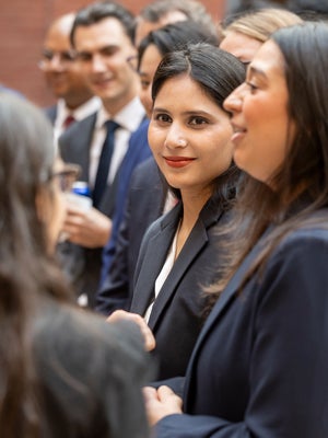 A group of H1-B students, professionally dressed networking at an event