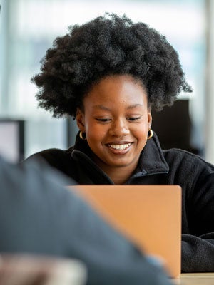 Smiling business analytics student working on a laptop in a classroom