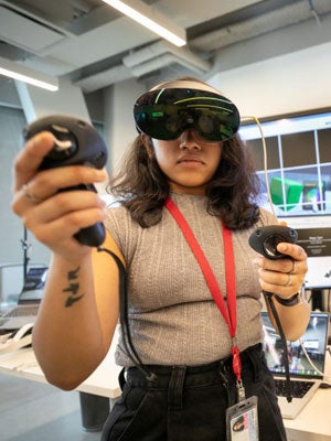 Business student using a VR headset and controllers in a Cornell Tech lab