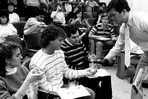 a teaching assistant pours a glass of wine for students in the wine course.