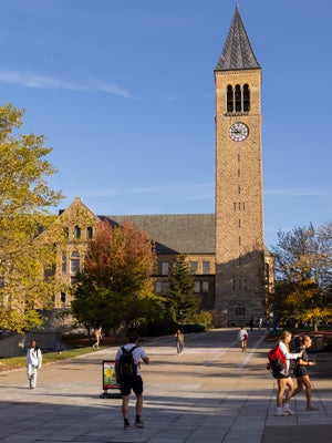 H1-B students walk across Cornell University's campus with McGraw Tower in the background