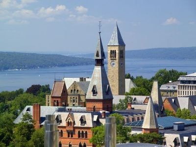 A view of Barnes Hall and the Cornell clock tower with Cayuga Lake int he background.