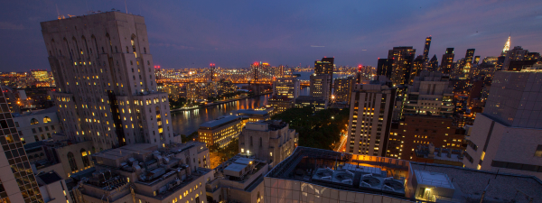 New York City skyline at night with Empire State Building in the far right of the sky