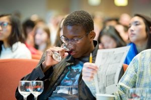 A student breathes in the aroma of a wine.
