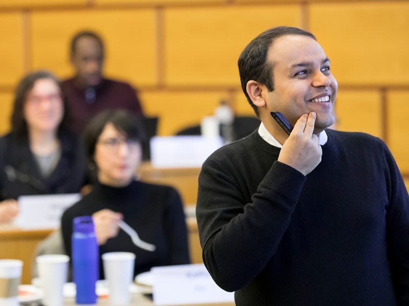 Cornell business faculty Karan Girotra smiles while teaching business students in a lively lecture hall.