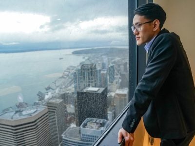 Student looking out a window at a skyline