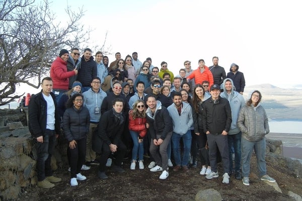 A large group poses for a photo at the top of a cliff