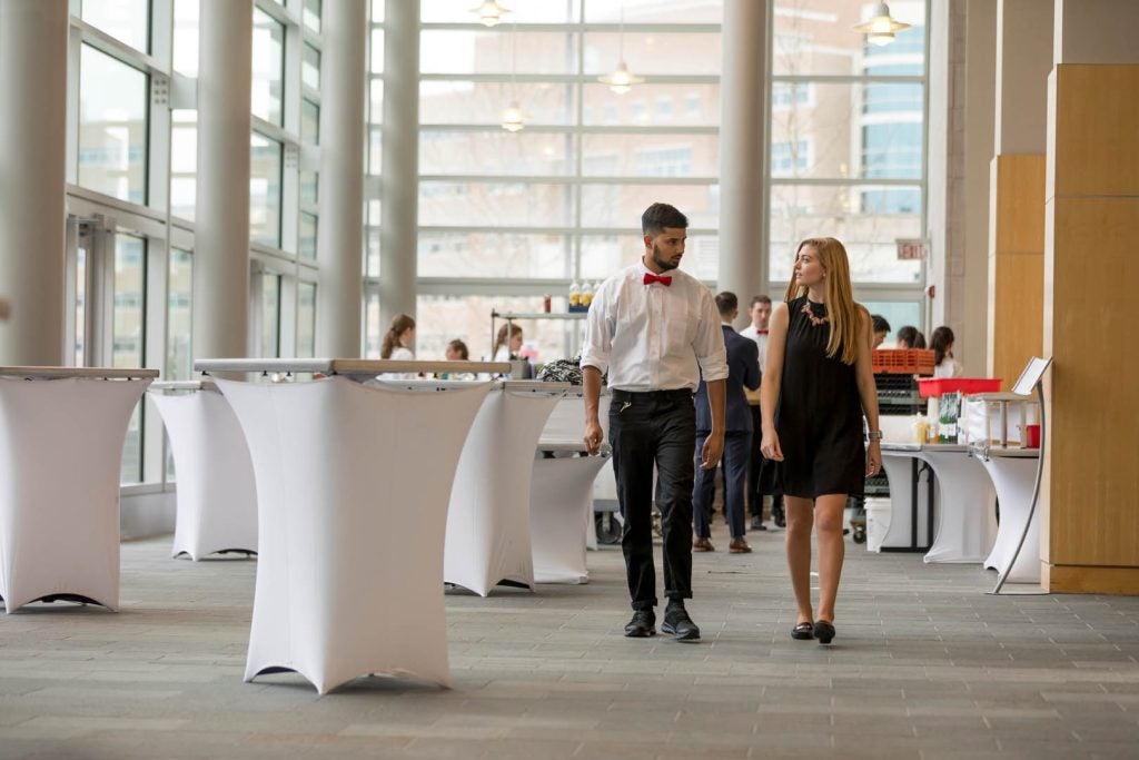 Two students walking down isles of event space chatting