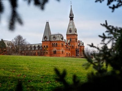 Sage Hall framed by trees branches and green grass in the foreground.