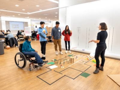 Image of five individuals collaborating over a proposed layout on the floor.
