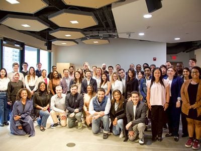 A group of 20-30 young adults posing for a photo in a large room.