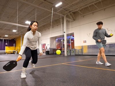 Image of a female and male student practicing pickleball at Pickleball Mania at the Shops at Ithaca Mall.