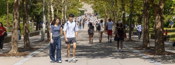 Many Cornell students walking on sunny day