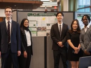 The CarbonWatch Kenya team smiles in front of their poster board.