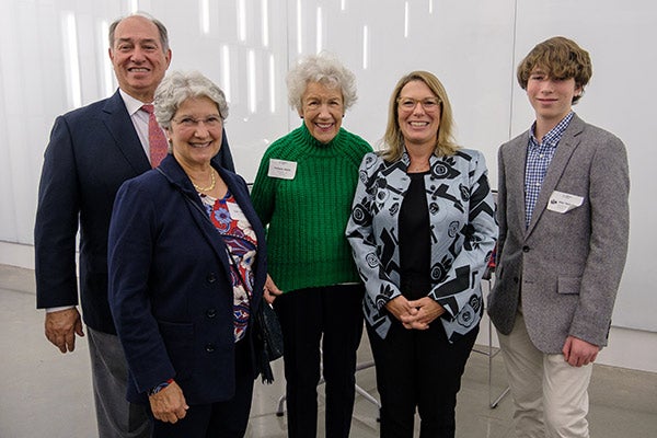 5 people standing side by side and smiling.
