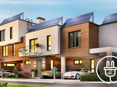 Modern apartment buildings with cars parked in front and charging at fast electric car charging stations