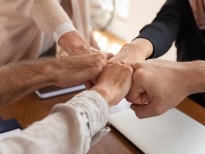 photo of five different people's fists joined together in a fist bump.