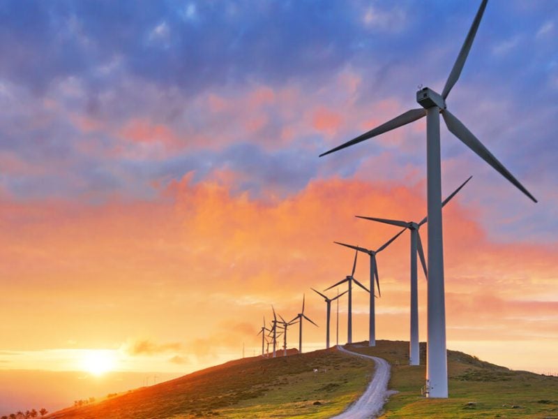 A row of windmills on a hill during sunset