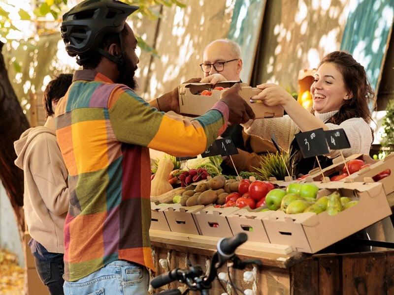 A biker collects fresh produce from a stand