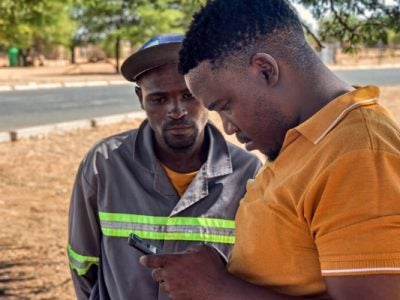 Image of two black men looking for information in a cell phone