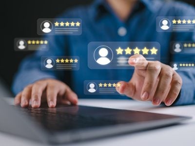A blurred image of a person using a laptop with consumer ratings and stars floating