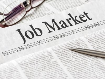 A newspaper with the headline Job Market, with glasses and a pen on top.