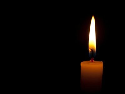 photo of a burning candle on a dark background.