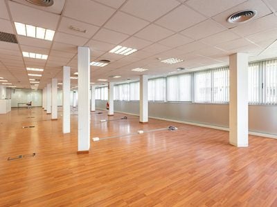 photo of an empty room with outlets and cable boxes built into the wood floor and windows along one side.