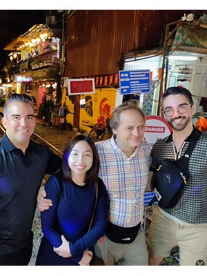 three men and a woman standing on a street in Hanoi with arms around each other