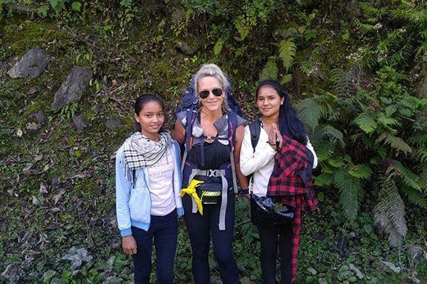 Anissa Buckley on the Anna Purna Circuit near Manang (12,000 feet) with two friendly schoolgirls and showing lush green vegetation in the background