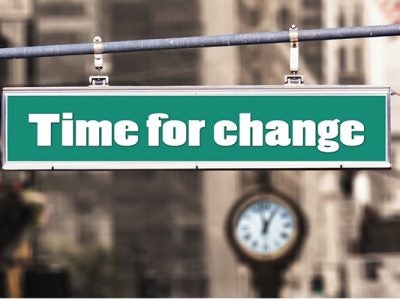 photo of what looks like a traffic sign on a city street that says "Time for change" with a large clock face below it