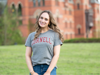 Photo of Carly Chasen wearing a gray Cornell t-shirt and standing in front of Sage Hall.
