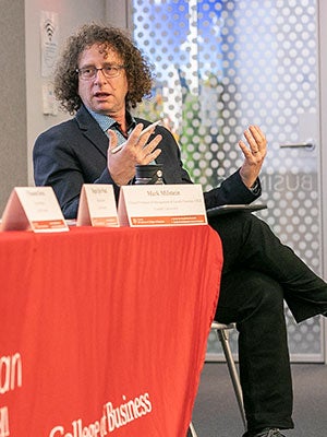 Mark Milstein seated at a table an gesturing with his hands while speaking.