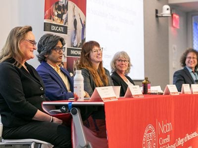 Three women and two men seated at the front of a room at a table draped with an SC Johnson College of Business banner.