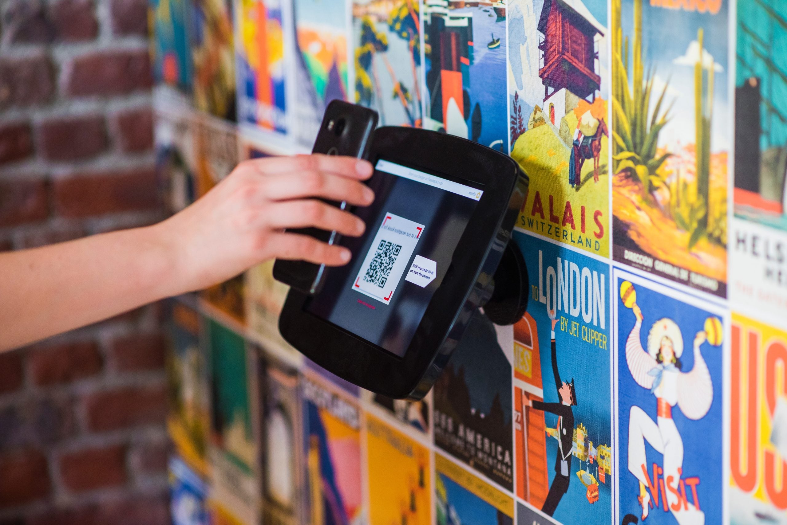 A person scans a QR code from a kiosk using their mobile phone. 