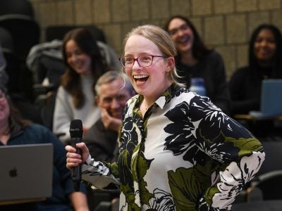 Photo of a smiling woman holding a microphone.